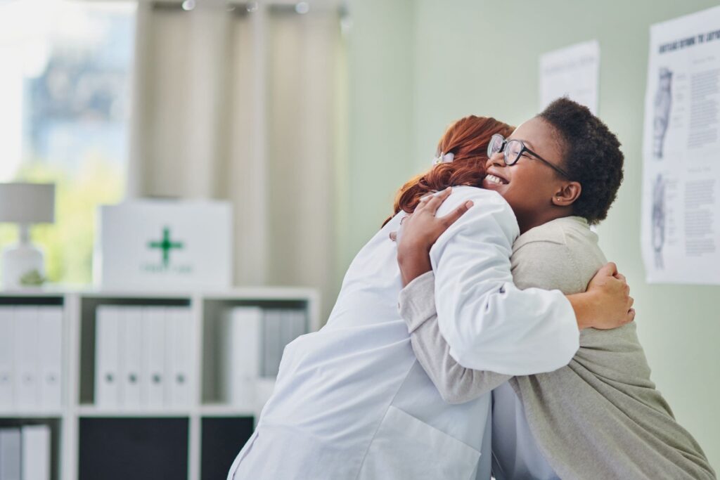 Doctor hugging her patient in the exam room